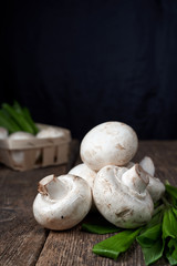 Fresh white mushrooms champignon in brown bowl on wooden background. Top view.