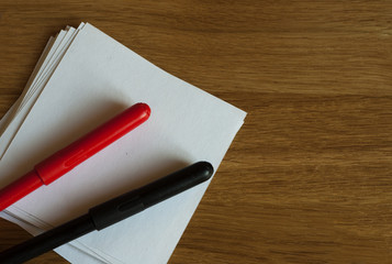 Red and black markers and white sticky note on wooden table. Copy space