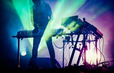 disc jokey mixing on stage over illuminated smoke background - summer music festival