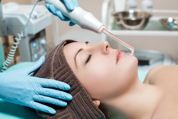 Face Beauty Treatment. Beautician makes Facial Darsonval Therapy for woman 