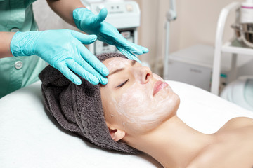 beautician applies face mask to beautiful young woman in Spa salon. cosmetic procedure skin care. Microdermabrasion