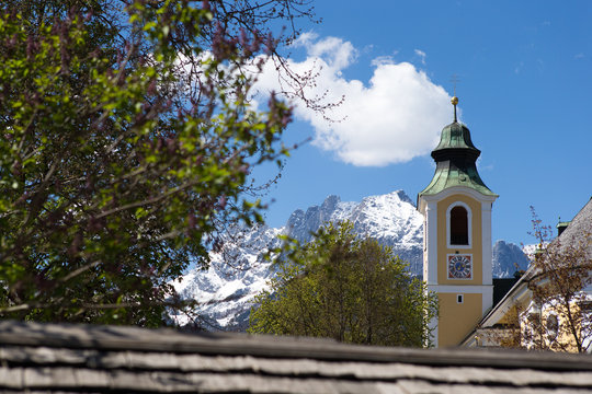 kirche im dorf bei st. johann in tirol mit schneebedeckten gipfel im hintergrund