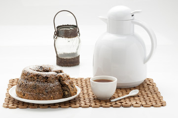 Chocolate cake with sugar decorated with caffe tea cups for tea weddings birthday breacks presented on white plate and decorated brown tablecloth