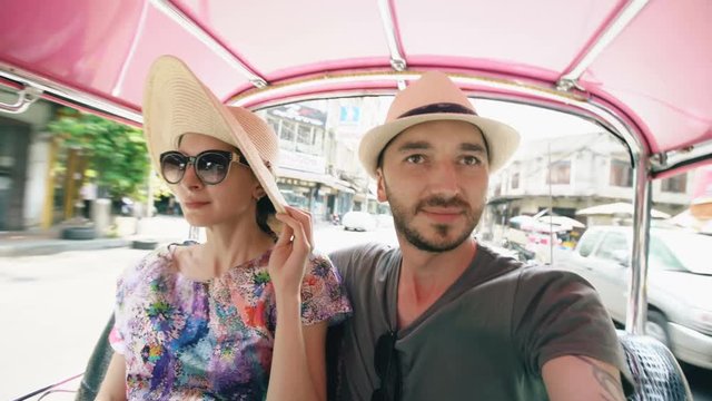 Young handsome man in hat with his girlfriend ride on traditional thai bus songteo . Couple travel Thailand during their honeymoon