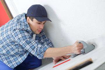male carpenter sets the baseboard on the floor