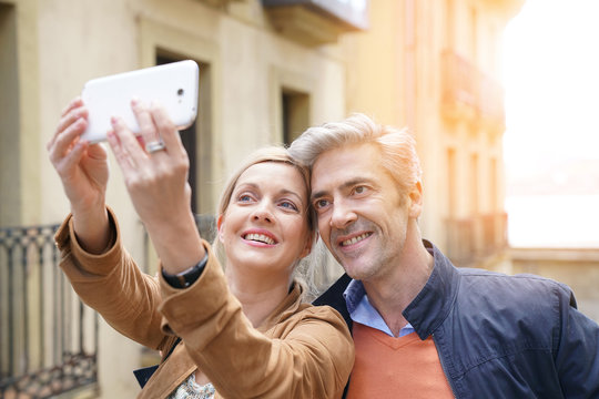Couple taking selfie picture with smartphone in European city