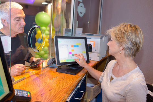 Woman Serving Man At Ticket Office