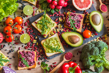 Healthy vegan food. Sandwiches and fresh vegetables on wooden background. Detox diet. Different colorful fresh juices. top view