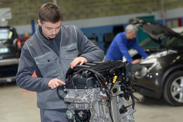 apprentice mechanic in auto shop working on car engine