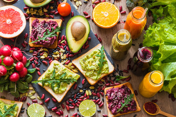 Healthy vegan food. Sandwiches and fresh vegetables on wooden background. Detox diet. Different colorful fresh juices. top view
