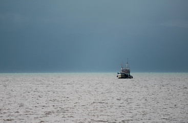 One fishing boat sailing under the stormy sky, Gulf of Thailand