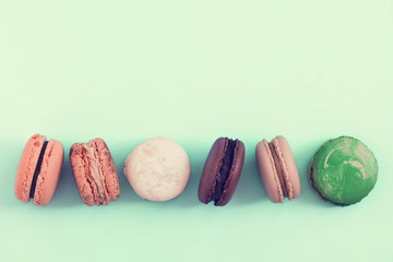 Raw of pastel colors assorted french  macaroons on a vintage toned bluebackground.  Copy space for text