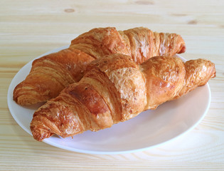 Pair of fresh whole wheat Croissant pastries served on a white plate 