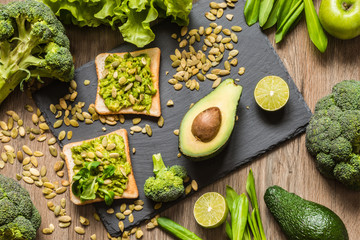 Healthy green food. Vegan sandwiches with avocado and vegetables on wooden background.