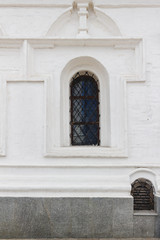 Latticed window in arches shape at white medieval church wall.