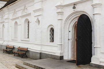 Fototapeta premium Open medieval door with metal decoration in white wall of old orthodox church.