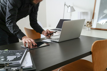 businessman or Designer using smart phone with latop and digital tablet computer and document on desk in modern office