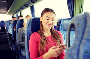 happy woman sitting in travel bus with smartphone