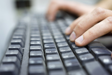 Hands of an office operator typing on dirty keyboard, a virus carrier that transmits diseases. Dof...