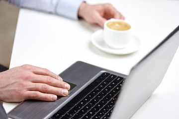 close up of male hands with laptop and coffee cup