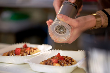 close up of cook hands spicing waffle