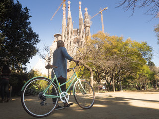 Young woman tourist with bicycle in front of Sagrada Familia in Barcelona 3