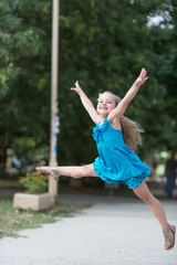 small baby girl with smiling face jumping in blue dress