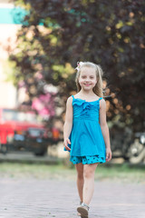 small baby girl with smiling face in blue dress outdoor