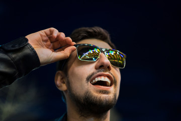 Smiling man in sunglasses with colorful reflection of night lights. Night city life