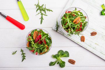 Fresh salad with strawberries, arugula and pecans on a wooden background