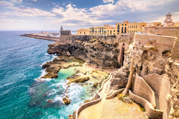 City walls, lighthouse and harbor in Melilla, Spanish province in Morocco. The rocky coast of the Mediterranean Sea. - obrazy, fototapety, plakaty