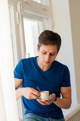 Man drinking coffee looking out the window