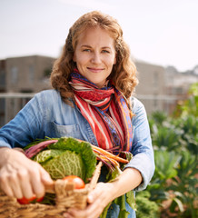 Friendly woman harvesting fresh vegetables from the rooftop greenhouse garden