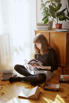 Young woman sitting on a floor and reading a book