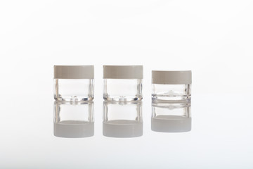 Empty transparent cosmetics jars on white background