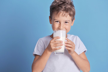 Cute kid drinking milk on blue background