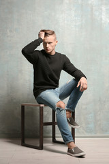 Handsome young man sitting near textured wall