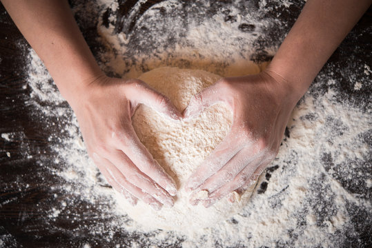 Woomens hands holding finished clean dough in heart shape
