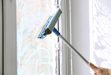 Hand of young man washing window in office