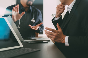 Medical co working concept,Doctor working with smart phone and digital tablet and laptop computer to meeting his team in modern office at hospital