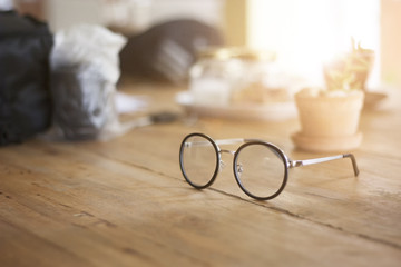 selective focus of eyeglasses on office wooden desk, vintage light.