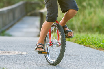 outdoor portrait of young boy riding a unicycle on natural background