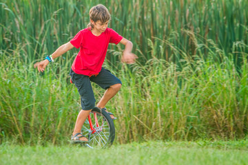outdoor portrait of young boy riding a unicycle on natural background © Alena Yakusheva