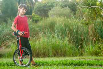 outdoor portrait of young boy riding a unicycle on natural background © Alena Yakusheva