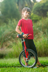 outdoor portrait of young boy riding a unicycle on natural background © Alena Yakusheva