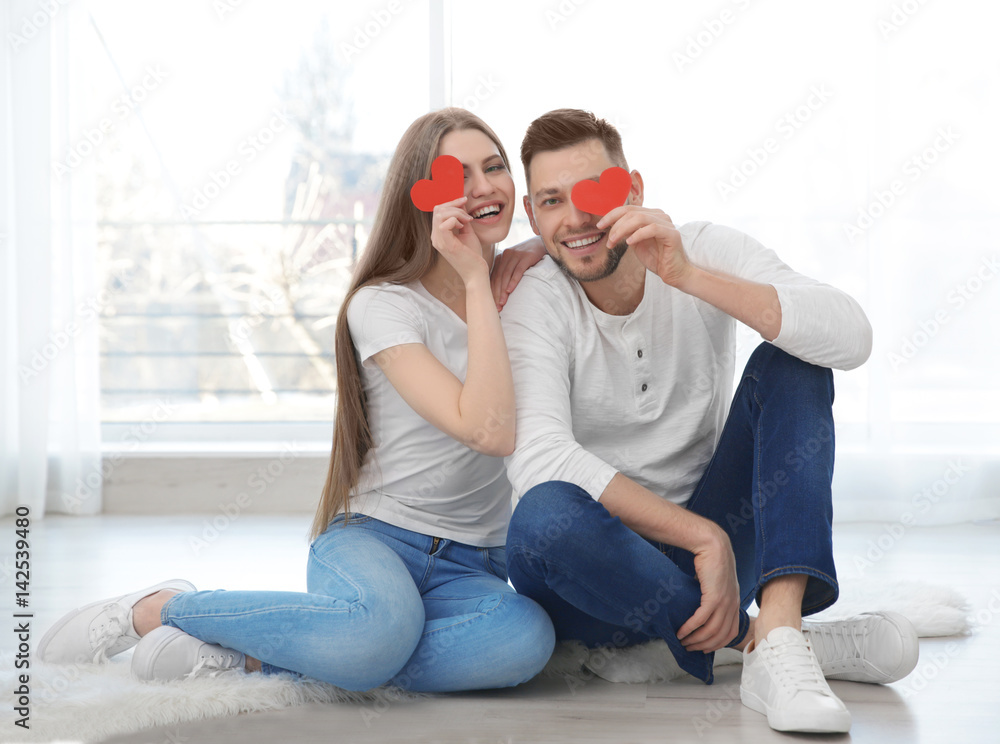 Canvas Prints Happy young couple with small red hearts sitting on floor at home