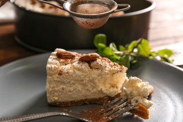 Sprinkling slice of cheesecake with cocoa powder