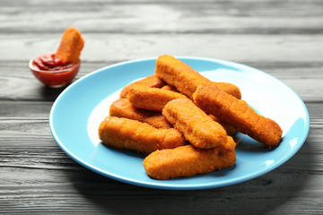 Plate with cheese sticks and ketchup sauce on wooden background