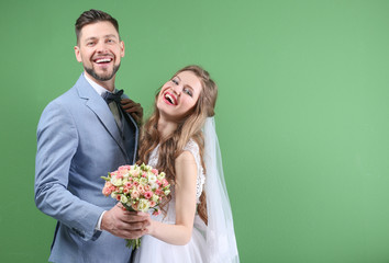 Happy wedding couple posing on color background