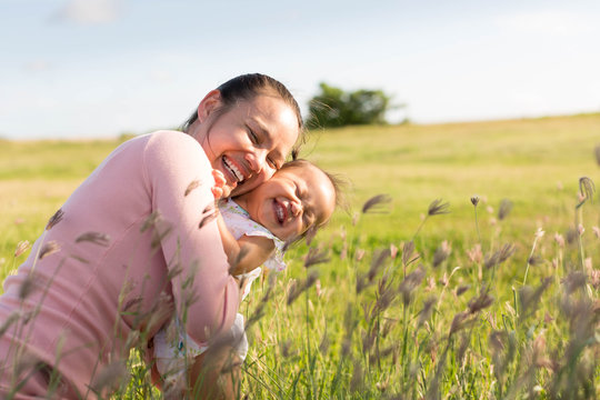 Mother and child playing and laughing in a outdoor green field